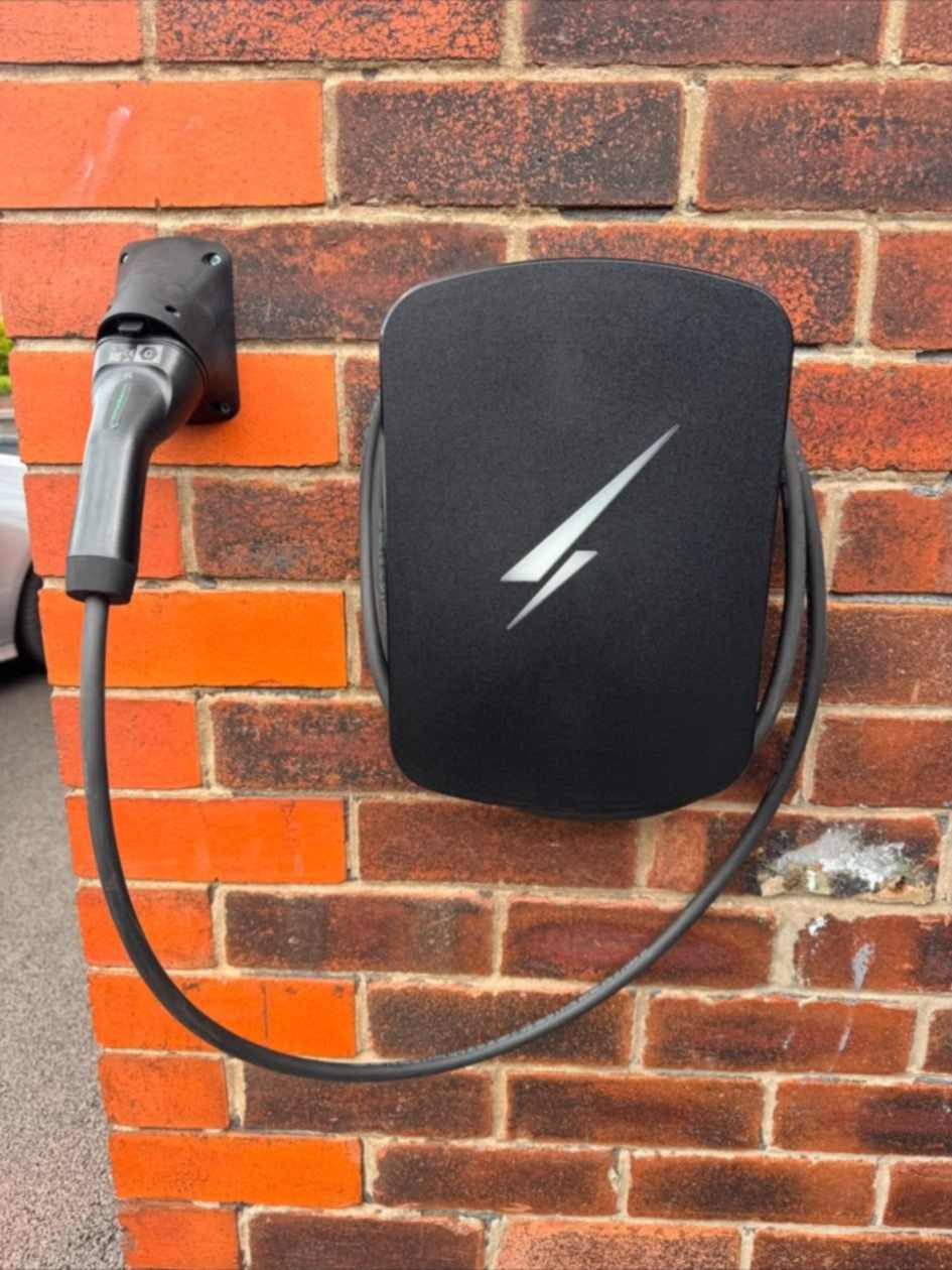 Hypervolt Home 3 Pro EV charge point on a brick wall in Ruislip, with the charging lead coiled around the unit and docked in a wall holster.