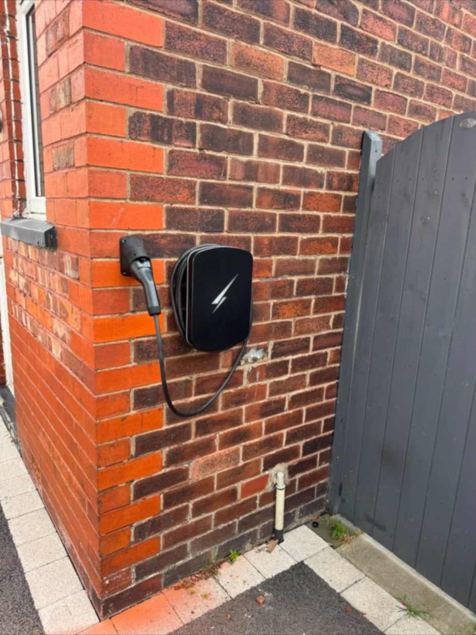 Wider view of the Hypervolt installation in Ruislip, on the side wall next to a grey timber gate.