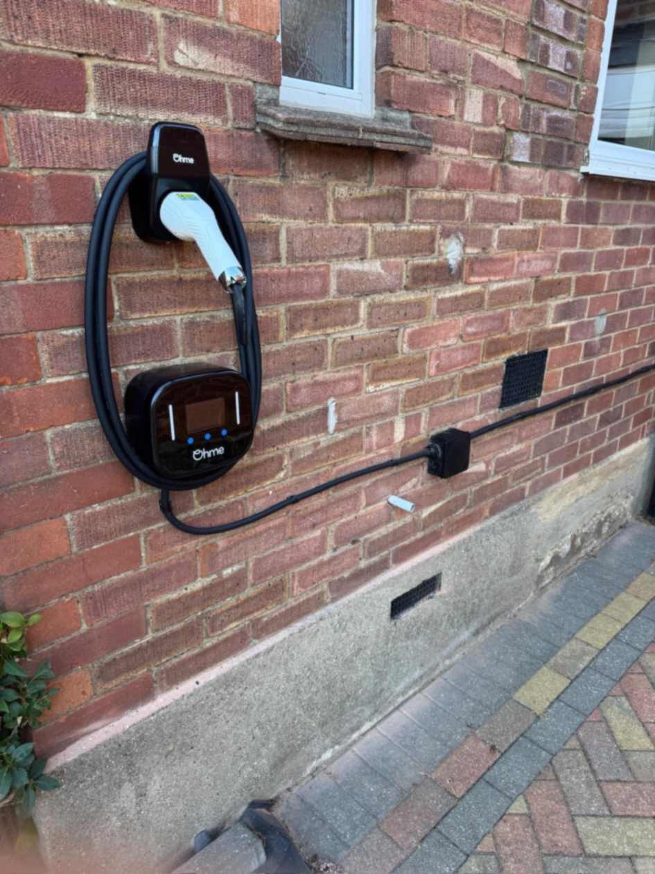 Angled view of the Ohme charge point installation in Ruislip, showing the supply cable run along the brickwork.