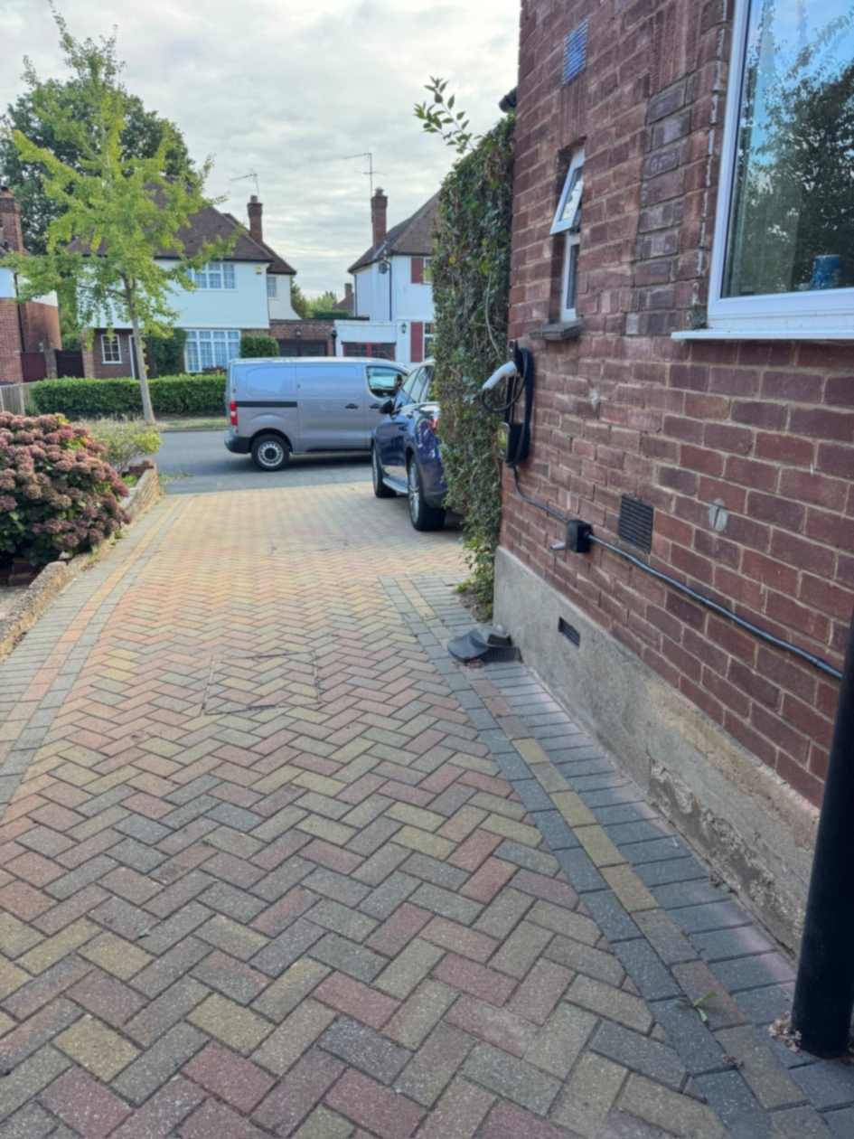 Wider view of the Ohme charge point beside the driveway of a red brick house in Ruislip.