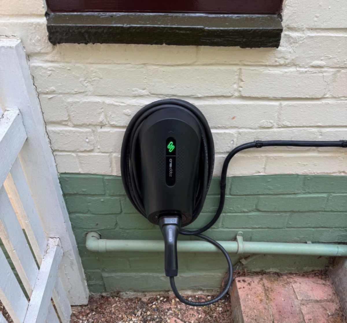 Wider view of the same zappi GLO installation in Beaconsfield, showing the charger positioned beside a side gate.